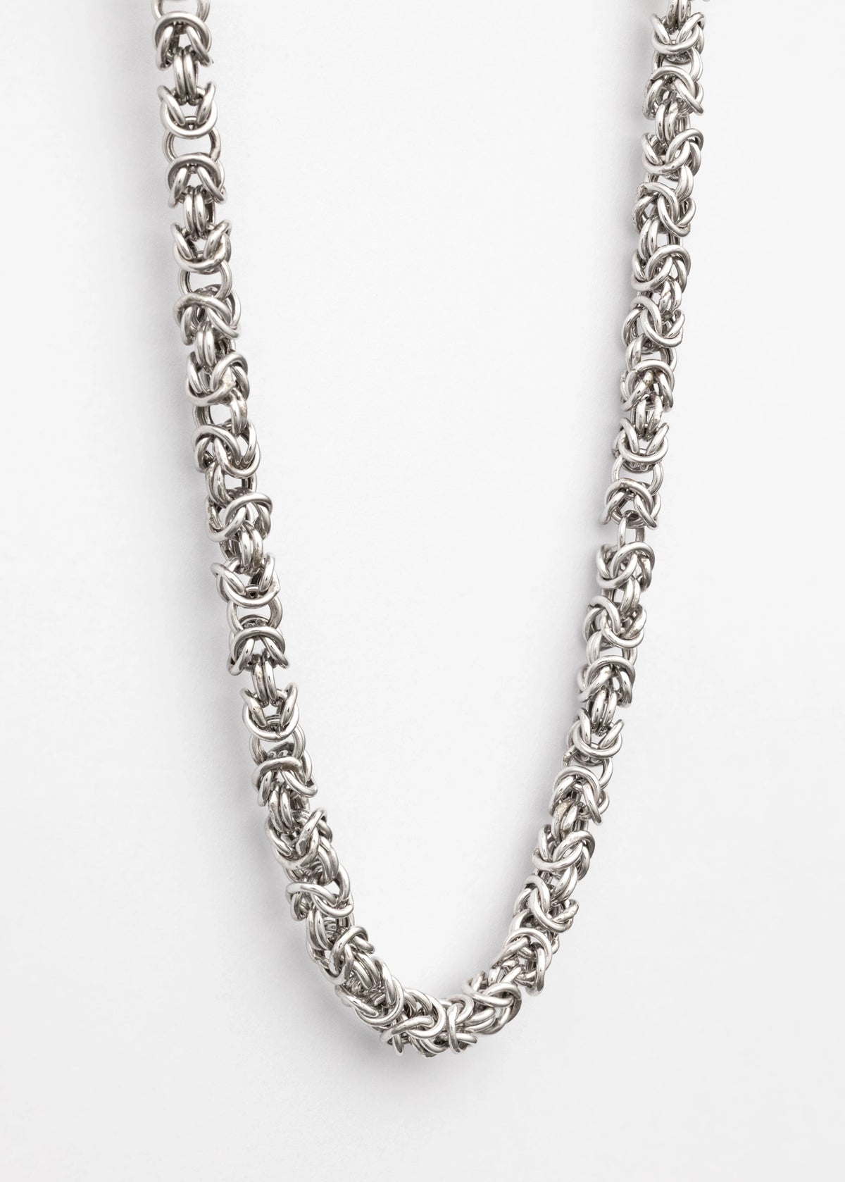 A close-up of a silver-toned chain necklace with a textured, interlocking link pattern, photographed against a clean white background.