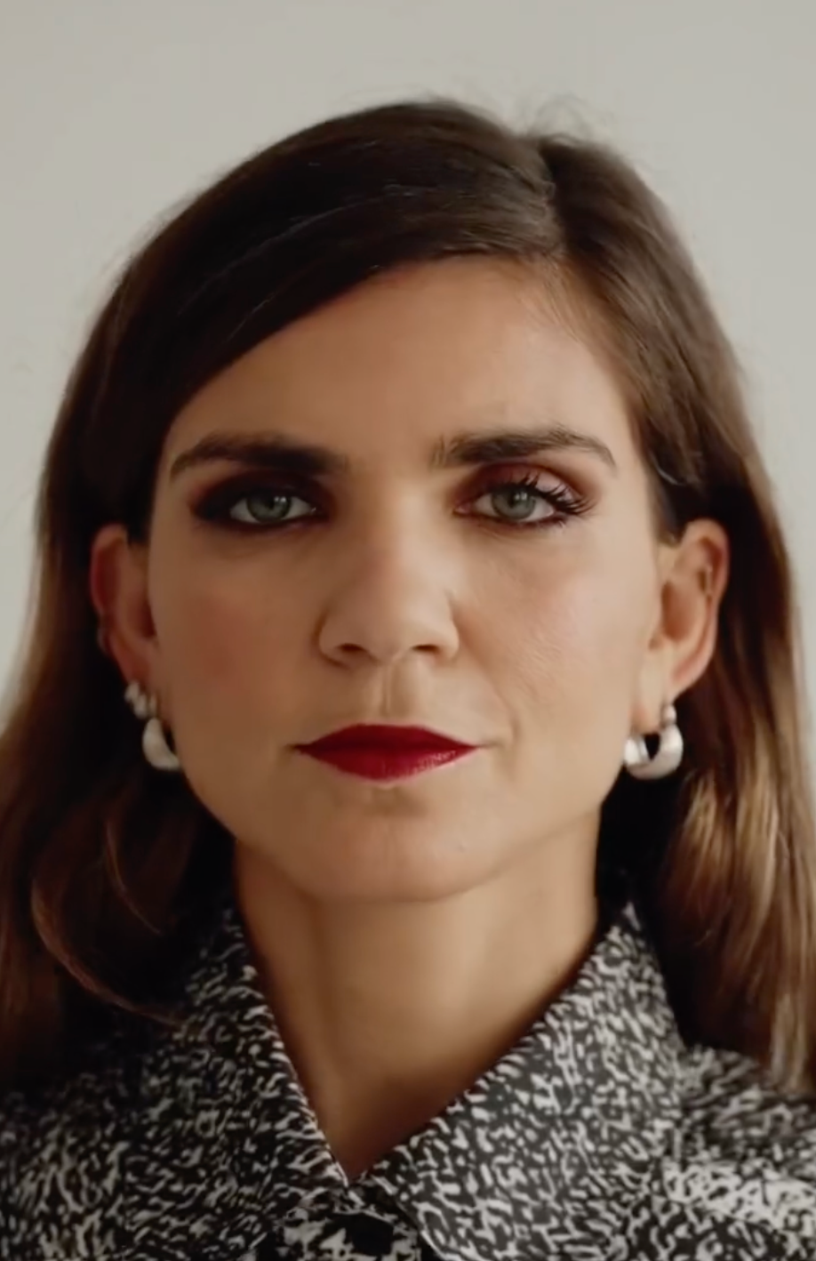 Close-up of a woman wearing CINCO jewelry, showing pearl earrings and a bold makeup look.
