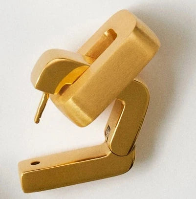 Collection of gold earrings on a light gray background