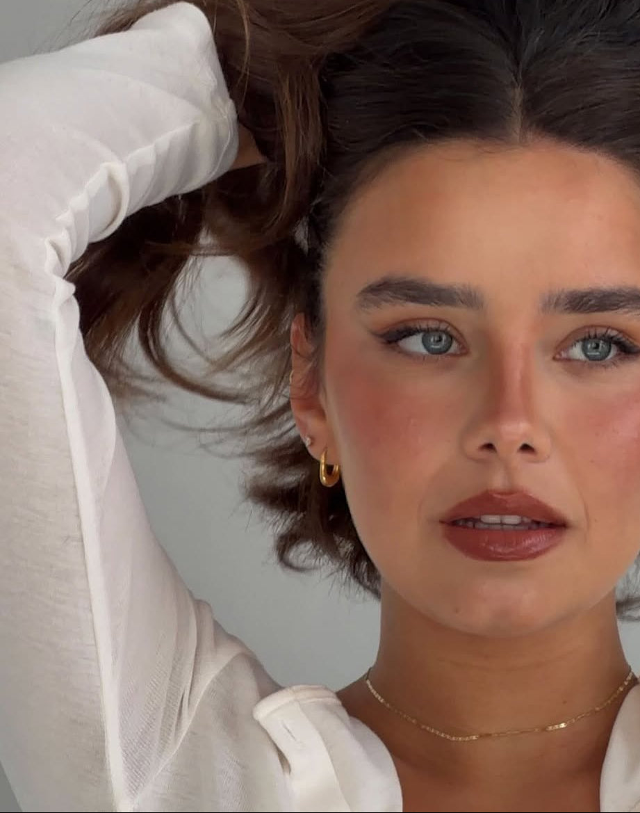 Close-up of a woman wearing silver 925  plated 24k yellow gold earrings and a gold choker. 