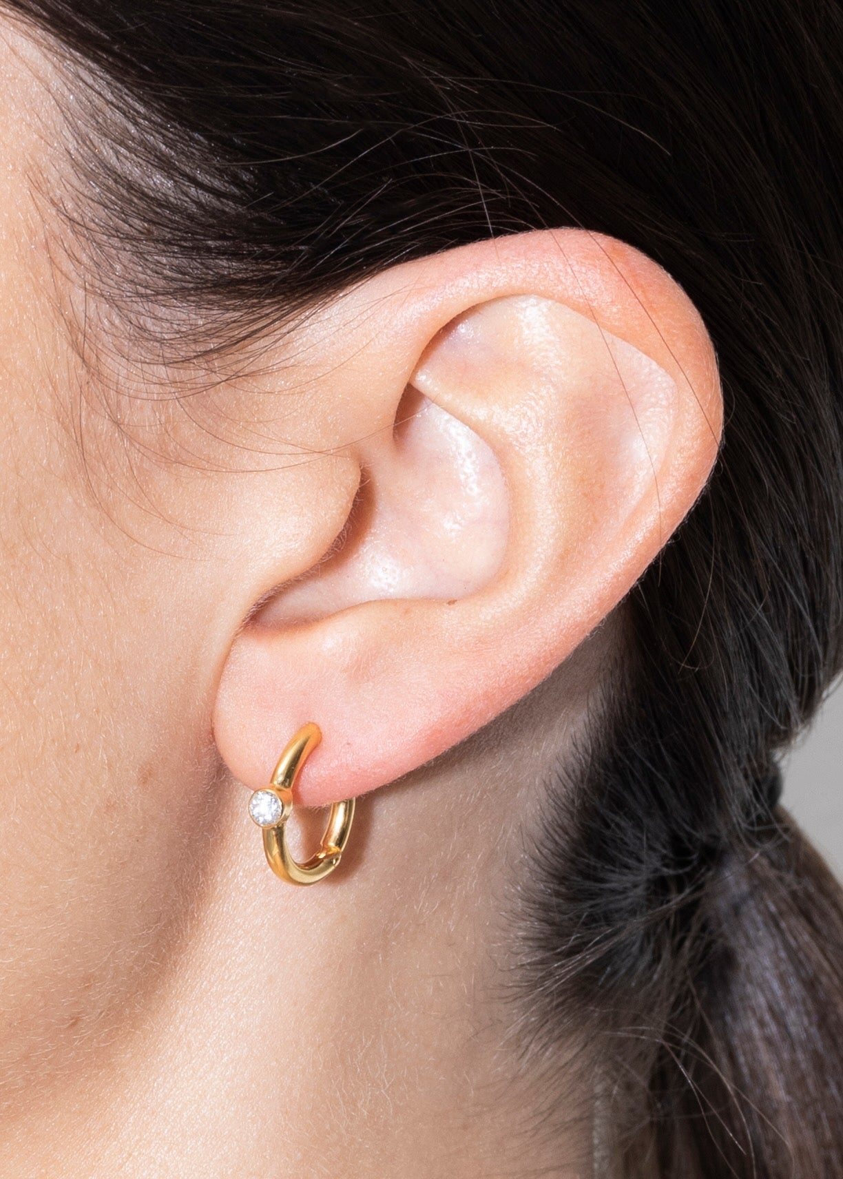 Detail of an ear with linda earrings gold