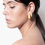 model wearing magda earrings and magda huggies in gold