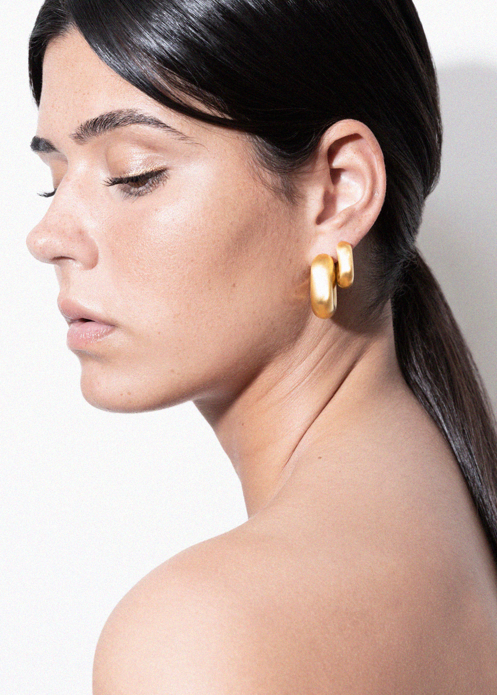 model wearing magda earrings and magda huggies in gold