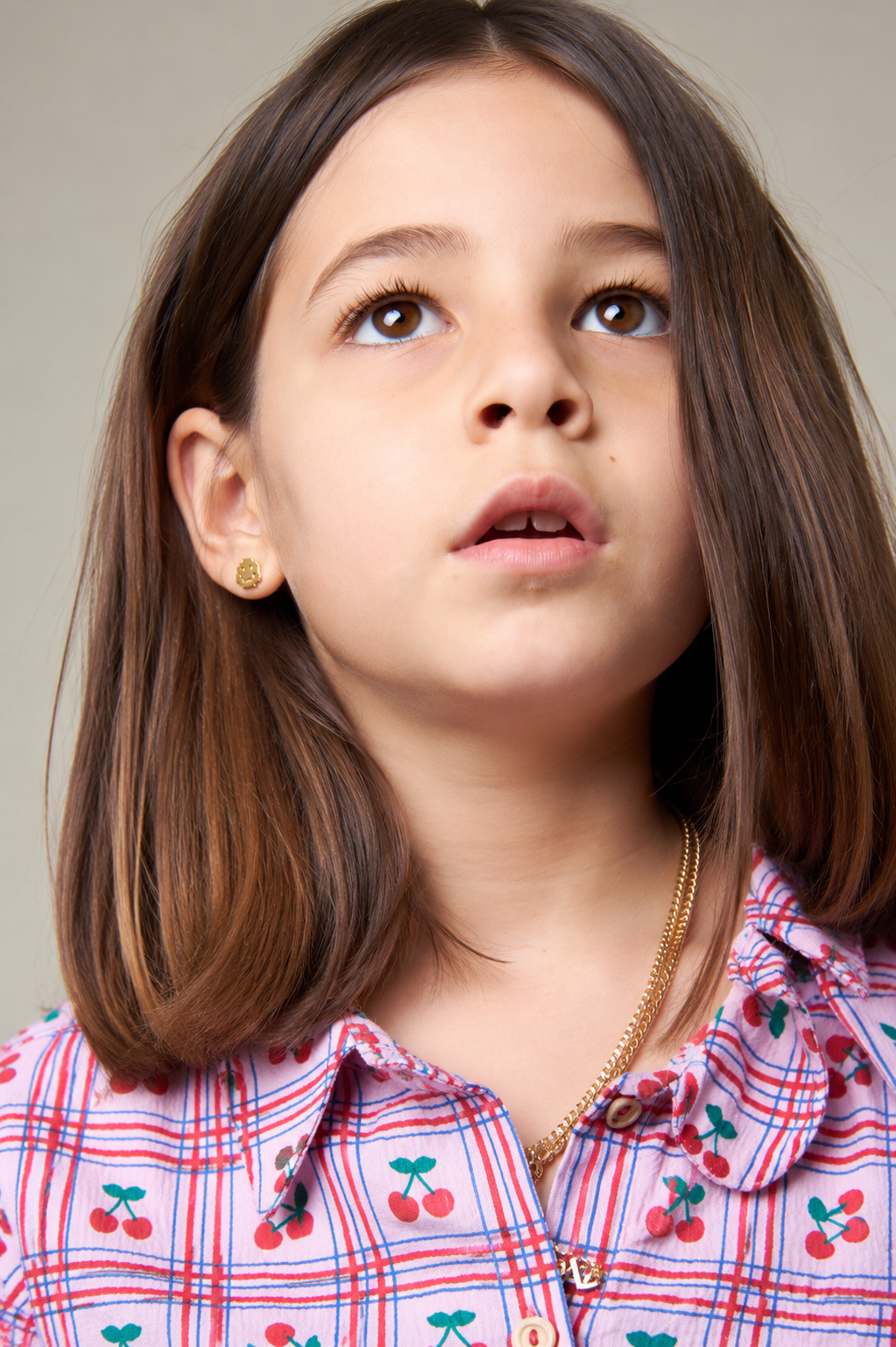 Jeune fille portant une chemise à carreaux avec un motif de cerises sur un fond neutre
