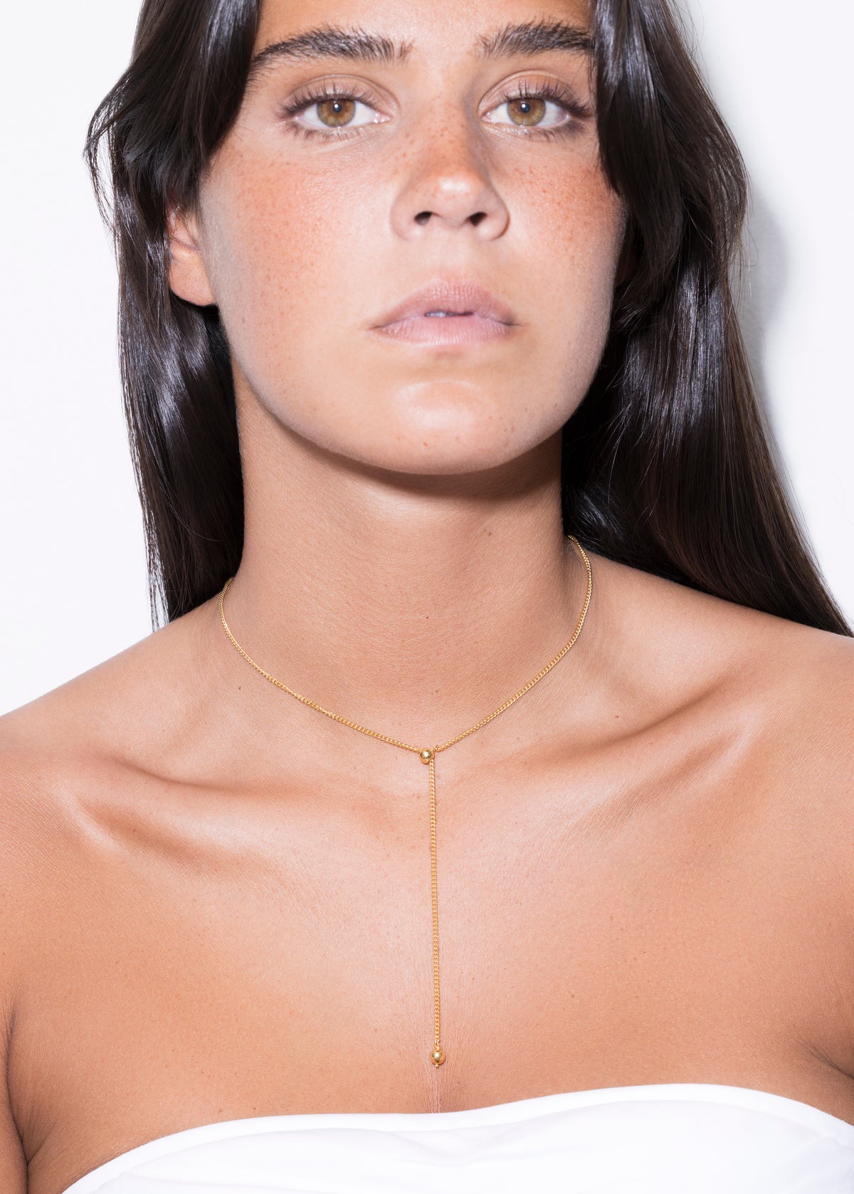 model wearing a gold scarlett necklace against a white background