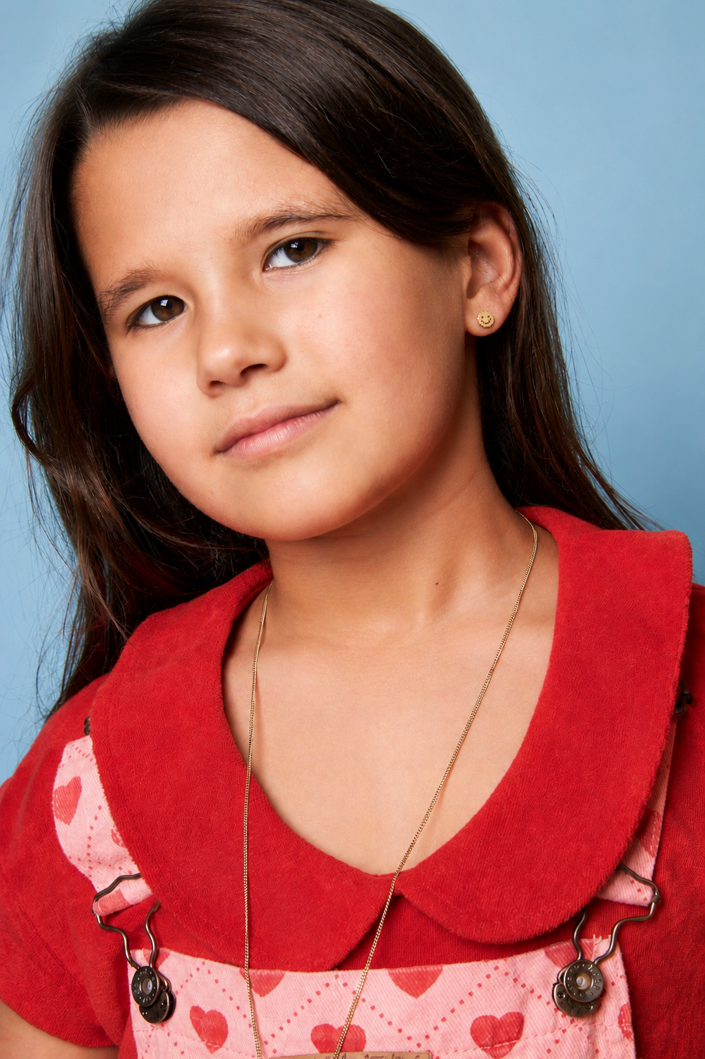 Jeune fille portant une chemise rouge avec un tablier à motifs de cœurs sur un fond bleu