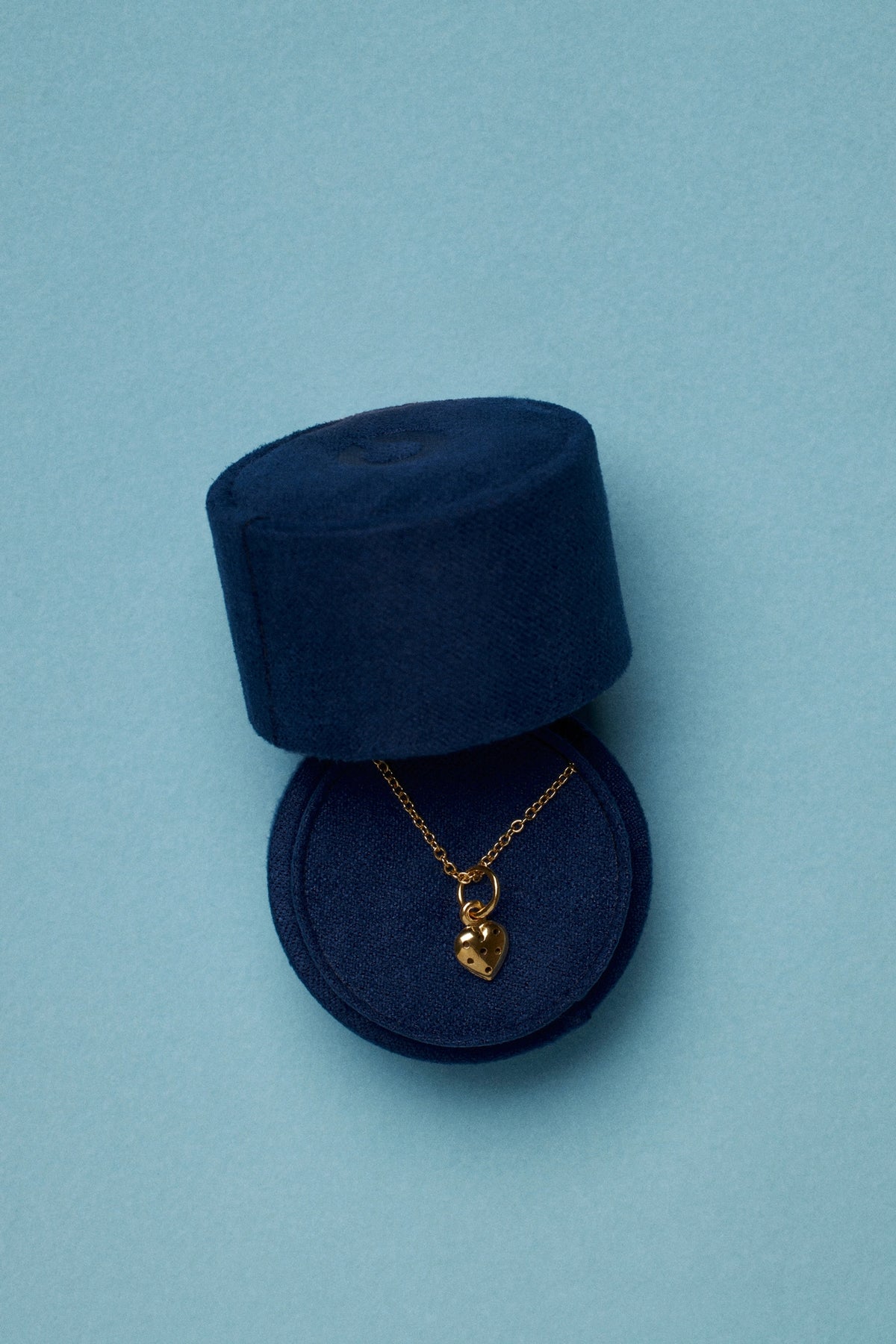 Tiny velvet jewelry box with gold heart necklace, showcasing an elegant gift presentation.