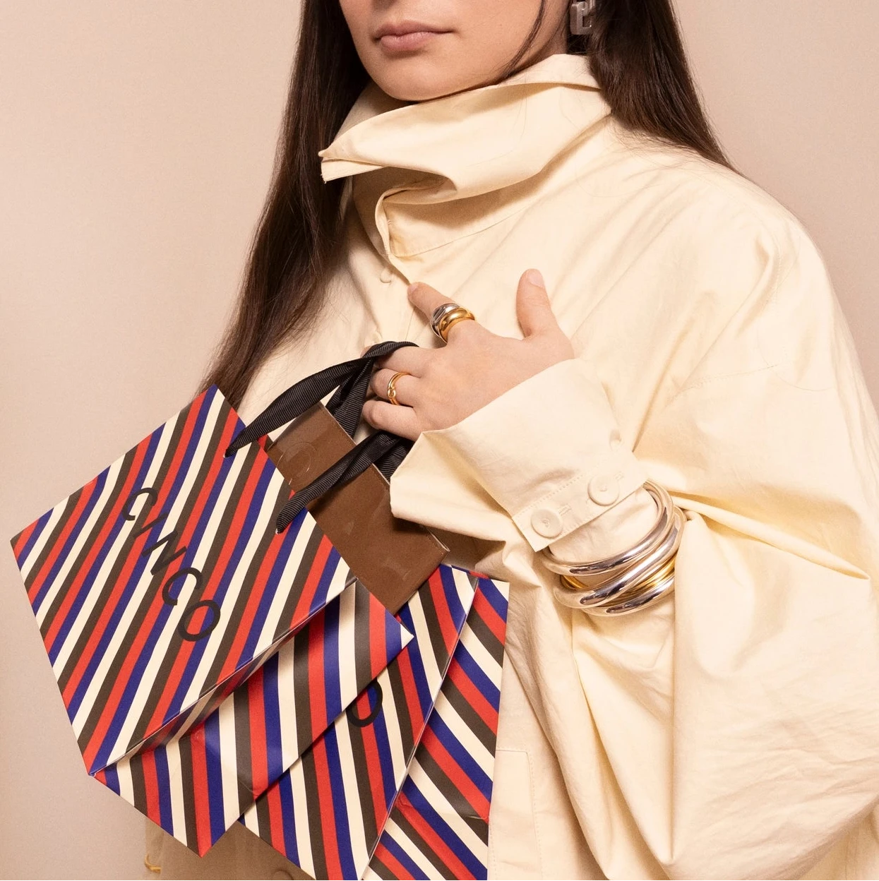 Woman holding a striped CINCO bag with shopping jewelry with discount